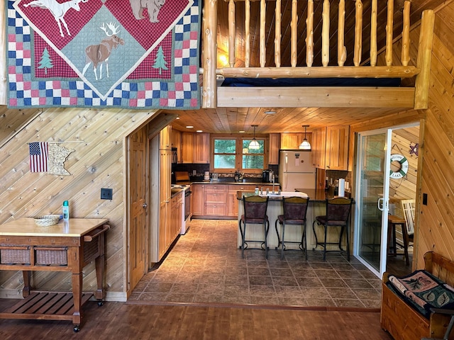 kitchen with wooden walls, dark countertops, a breakfast bar area, freestanding refrigerator, and a peninsula
