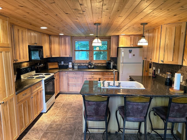 kitchen with freestanding refrigerator, a peninsula, black microwave, range with electric stovetop, and a sink