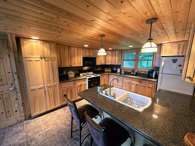 kitchen with freestanding refrigerator, a peninsula, black microwave, a sink, and range with electric cooktop