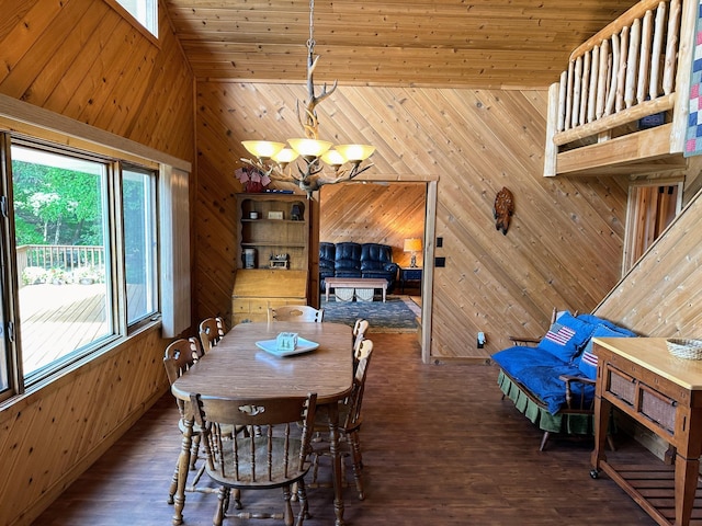 dining room with high vaulted ceiling, wood walls, wood finished floors, and an inviting chandelier