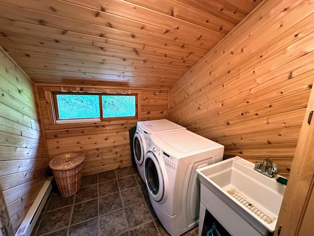 clothes washing area with separate washer and dryer, a sink, wooden walls, and laundry area