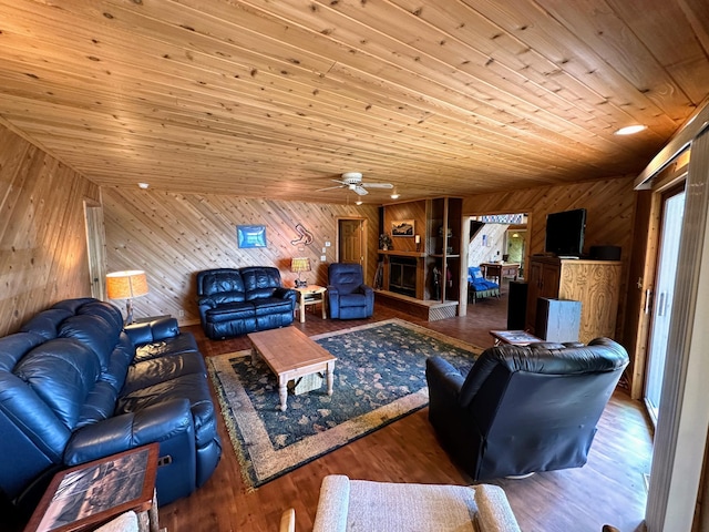 living room featuring a ceiling fan, wood walls, wood ceiling, and wood finished floors