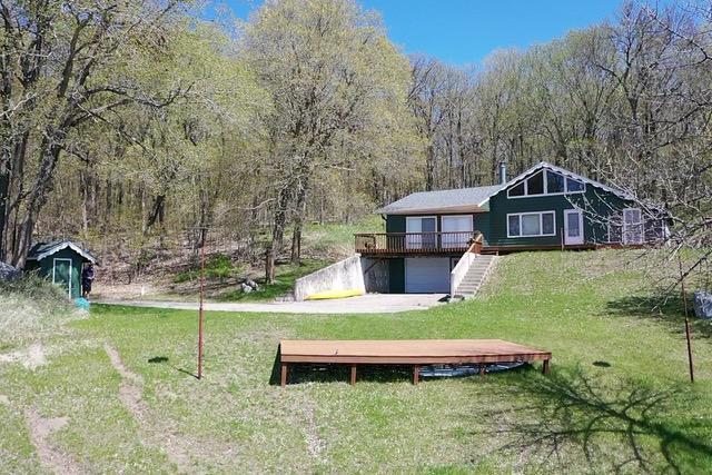 36018 504th St, Hobart Twp, MN 56544 - view of green lawn with stairs, a garage, a view of trees, a deck, and concrete driveway