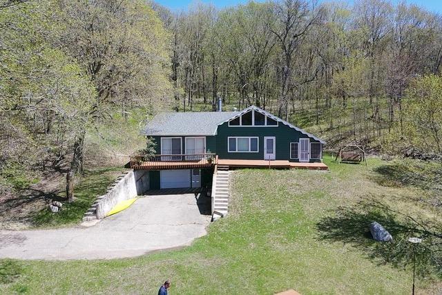 36018 504th St, Hobart Twp, MN 56544 - view of front of property with asphalt driveway, a forest view, a garage, and a deck