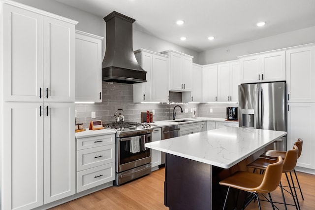 kitchen featuring stainless steel appliances, custom exhaust hood, a sink, a breakfast bar, and a center island