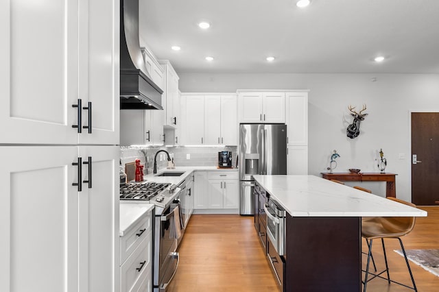 kitchen featuring stainless steel appliances, premium range hood, a sink, a center island, and a breakfast bar
