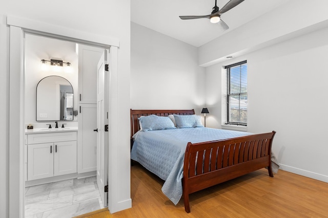 bedroom with a sink, baseboards, ensuite bathroom, lofted ceiling, and ceiling fan