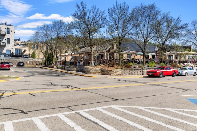 view of asphalt road with a residential view, curbs, street lighting, and sidewalks