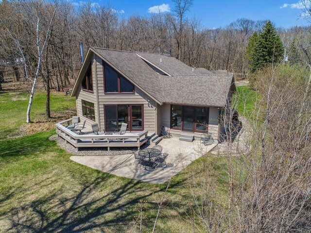 1844 Mount Carmel Dr NE, Alexandria, MN 56308 - rear view of house featuring roof with shingles, a patio area, a fire pit, a yard, and a wooden deck