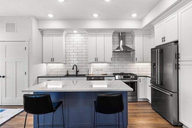 517 2nd St Unit 303, Hudson, WI 54016 - kitchen with stainless steel appliances, wall chimney range hood, a sink, a kitchen bar, and dark wood-style flooring