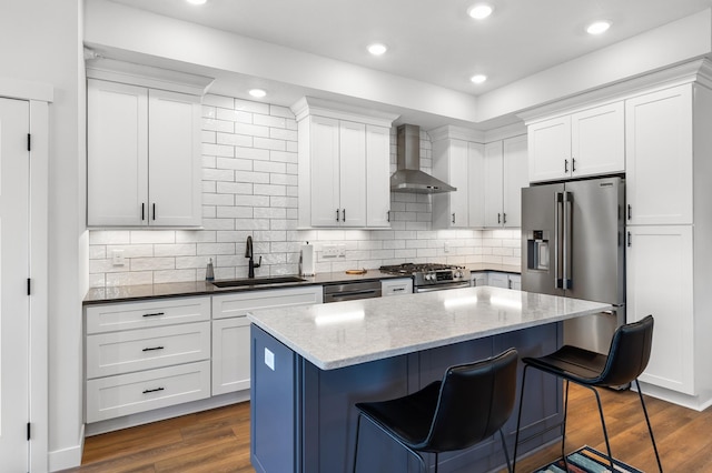 517 2nd St Unit 303, Hudson, WI 54016 - kitchen featuring wall chimney range hood, a sink, stainless steel appliances, a breakfast bar area, and a kitchen island