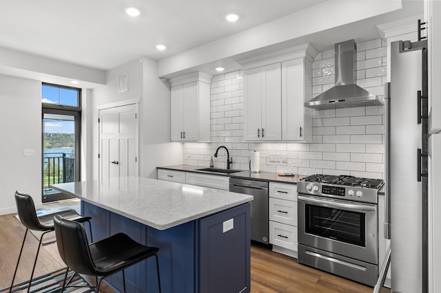 517 2nd St Unit 303, Hudson, WI 54016 - kitchen with stainless steel appliances, wall chimney exhaust hood, a sink, a breakfast bar, and a kitchen island