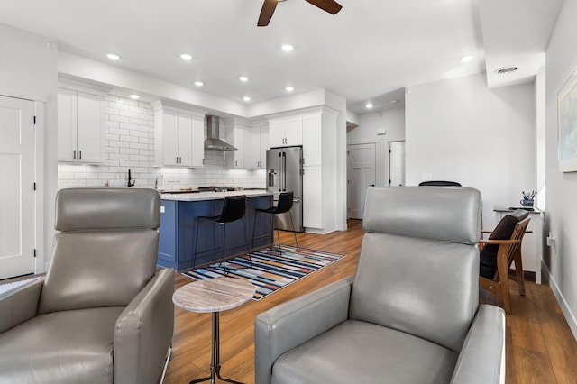 517 2nd St Unit 303, Hudson, WI 54016 - kitchen with stainless steel appliances, wall chimney exhaust hood, light wood-style floors, white cabinetry, and a ceiling fan
