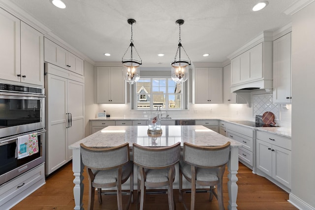 kitchen with a kitchen bar, a center island, tasteful backsplash, double oven, and paneled built in refrigerator