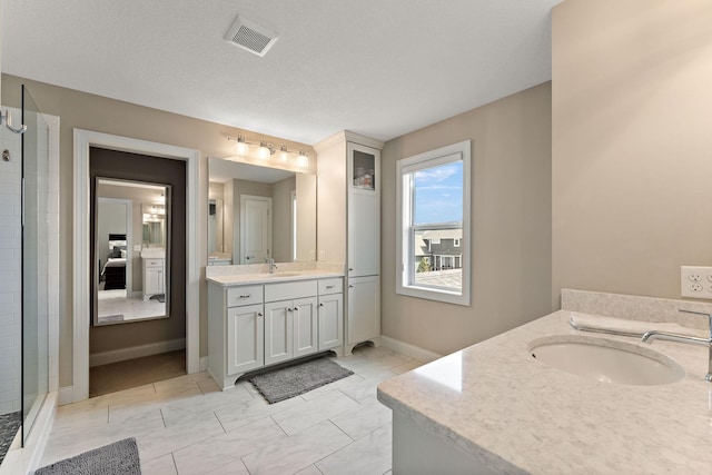 full bathroom featuring visible vents, a sink, two vanities, and a stall shower