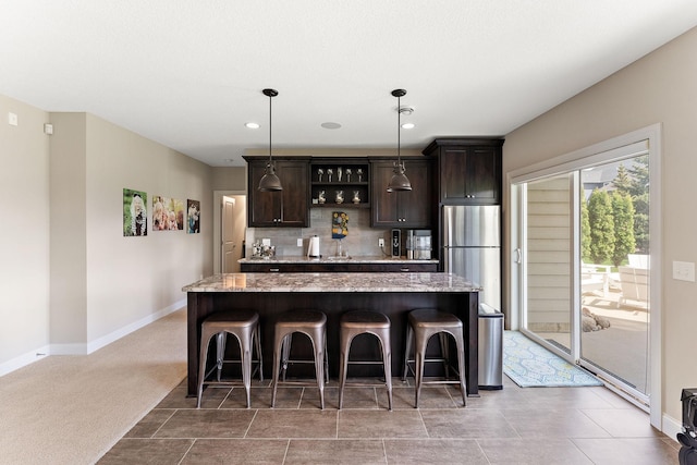 kitchen featuring freestanding refrigerator, dark brown cabinets, a kitchen island, and a kitchen bar