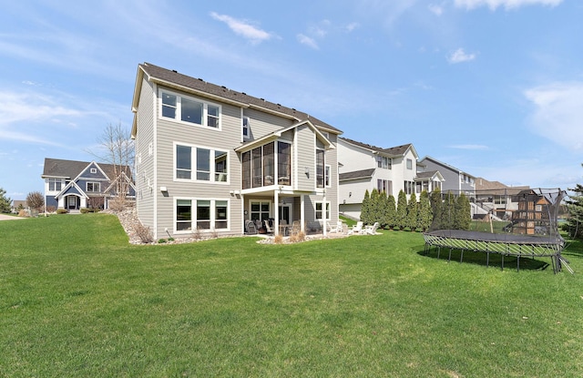 rear view of property with a residential view, a sunroom, a trampoline, and a lawn