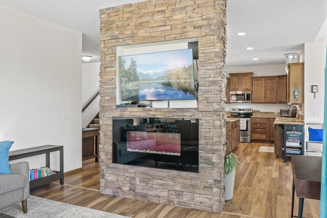 2895 Thunder Bay Ct, Little Canada, MN 55117 - living room with wood finished floors, a fireplace, a textured ceiling, and recessed lighting