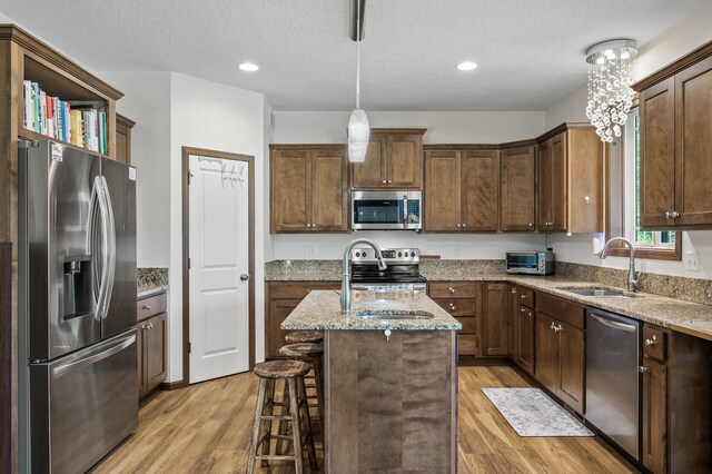 2895 Thunder Bay Ct, Little Canada, MN 55117 - kitchen featuring stainless steel appliances, a sink, light wood-style floors, light stone countertops, and a textured ceiling
