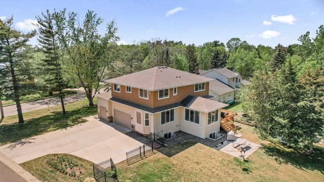2895 Thunder Bay Ct, Little Canada, MN 55117 - back of property featuring concrete driveway, a shingled roof, a garage, stairway, and a forest view