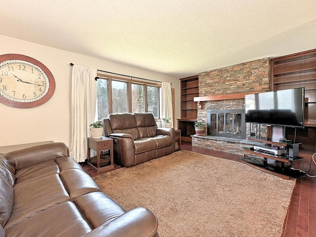 living area with a fireplace, built in features, a textured ceiling, and wood finished floors