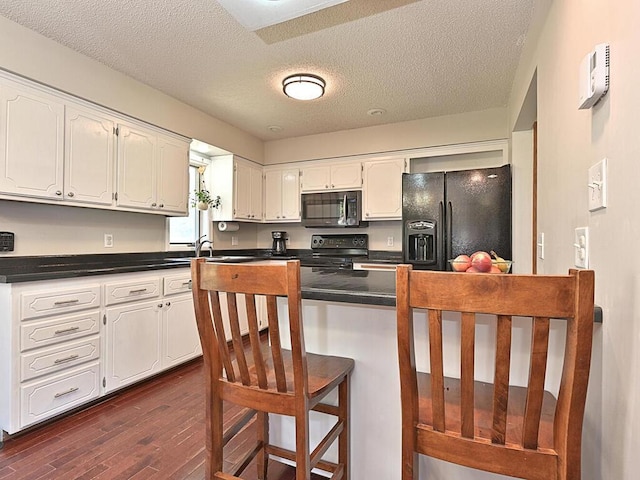 kitchen with dark countertops, dark wood-style flooring, black appliances, and white cabinets