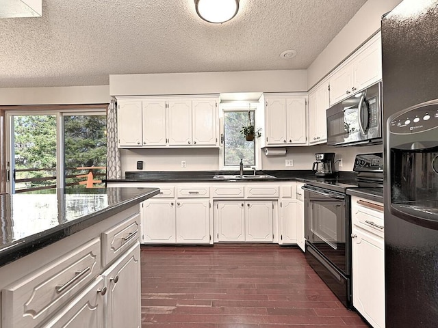 kitchen featuring a sink, dark countertops, a textured ceiling, white cabinetry, and black appliances