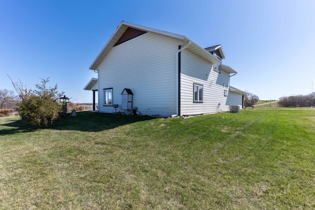view of side of home featuring a lawn and central AC