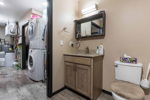 laundry room with a sink, light wood-style floors, laundry area, and stacked washer and dryer