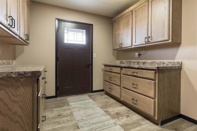 laundry room featuring baseboards and light wood finished floors