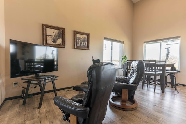living area featuring baseboards, a high ceiling, and wood finished floors