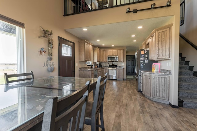 dining room featuring stairs, recessed lighting, plenty of natural light, and wood finished floors
