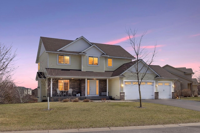 view of front of property with a front lawn, aphalt driveway, covered porch, and a garage