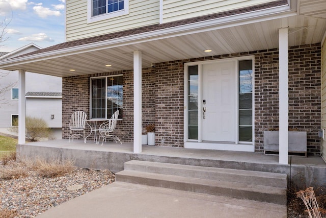 property entrance featuring brick siding and covered porch