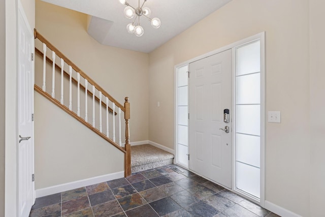 entrance foyer with a chandelier, baseboards, stone finish floor, and stairway