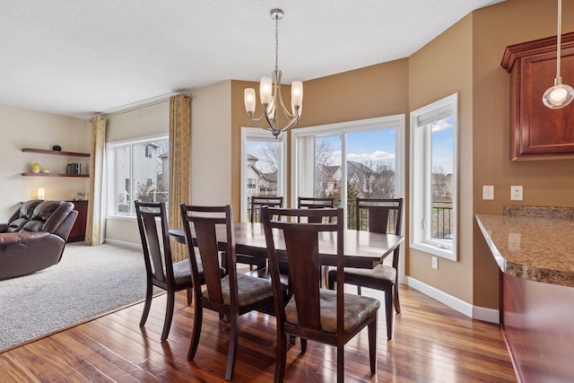 dining room with a notable chandelier, hardwood / wood-style floors, and baseboards