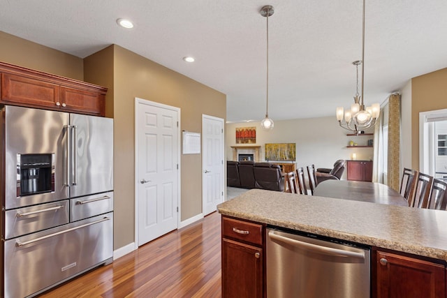 kitchen featuring pendant lighting, a chandelier, open floor plan, dark wood-style floors, and appliances with stainless steel finishes