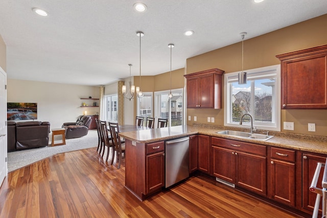 kitchen featuring a sink, dark wood finished floors, pendant lighting, open floor plan, and stainless steel dishwasher