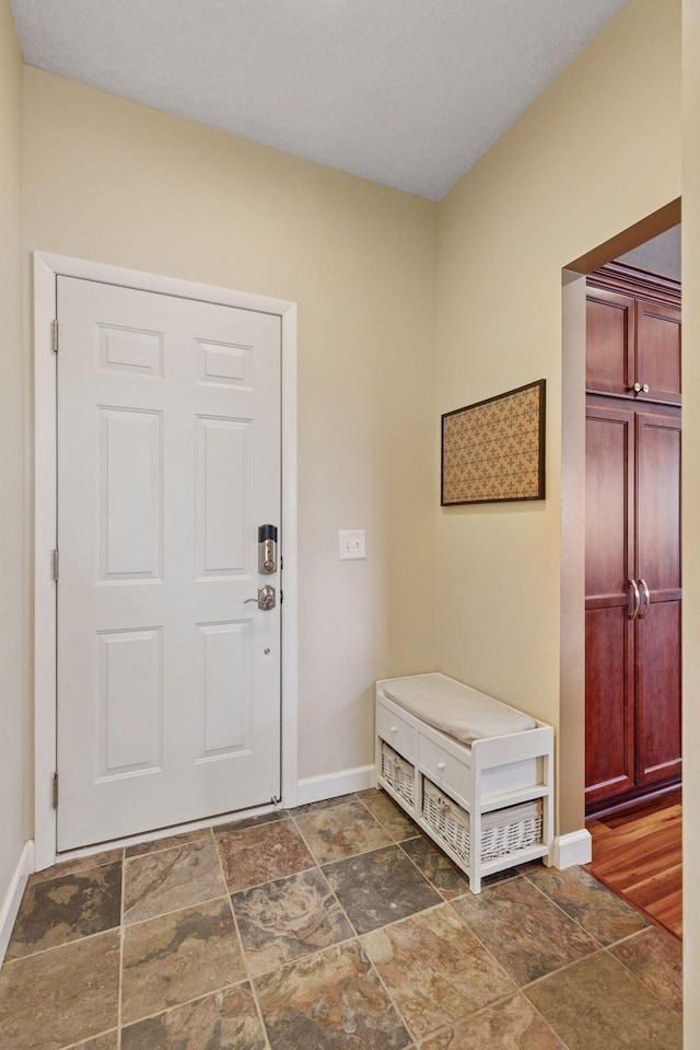 entrance foyer with baseboards and stone finish floor