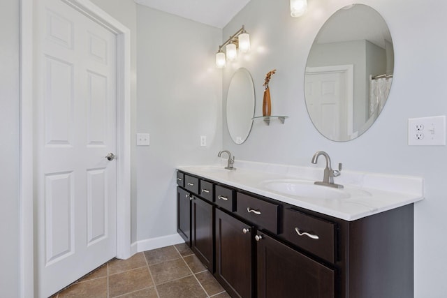 full bathroom featuring double vanity, baseboards, and a sink