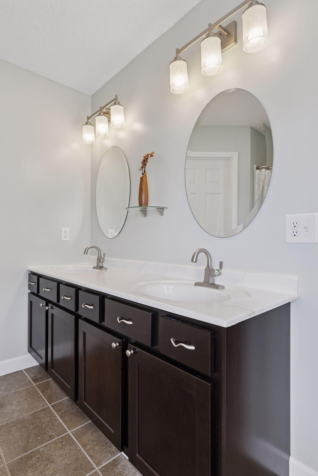 bathroom with a sink, double vanity, baseboards, and tile patterned flooring