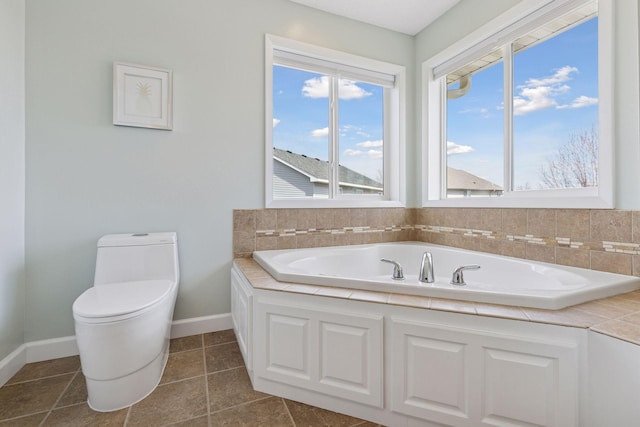 full bath with baseboards, tile patterned floors, a garden tub, and toilet