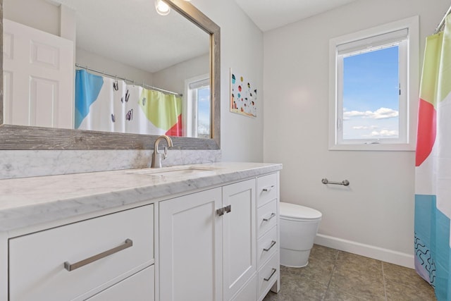 bathroom featuring toilet, baseboards, vanity, and a healthy amount of sunlight