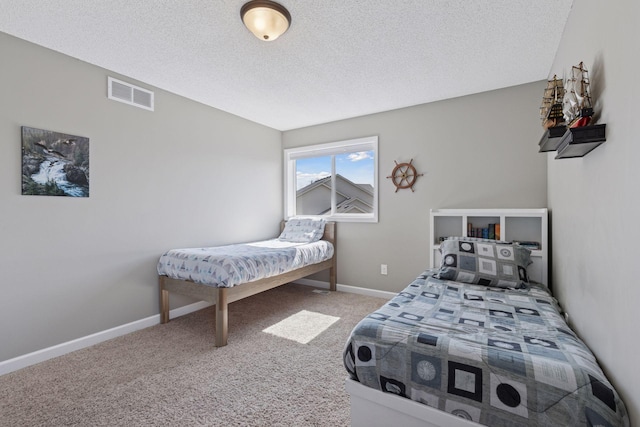 bedroom with a textured ceiling, carpet flooring, baseboards, and visible vents