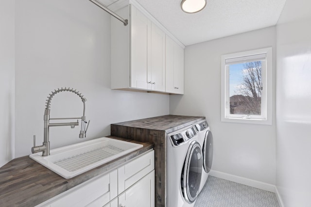 laundry area featuring cabinet space, washing machine and clothes dryer, baseboards, and a sink