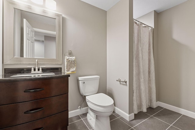 bathroom with toilet, baseboards, tile patterned floors, and vanity