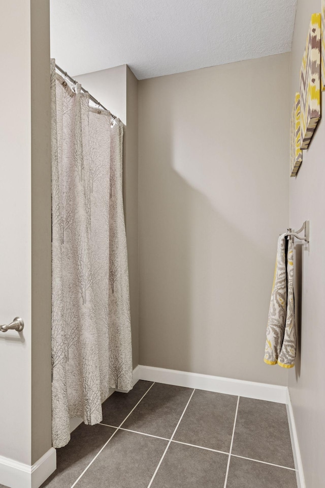 bathroom featuring a textured ceiling, a shower with shower curtain, and baseboards