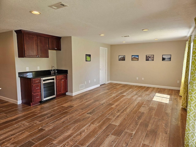 kitchen featuring dark countertops, wine cooler, dark wood-type flooring, and visible vents
