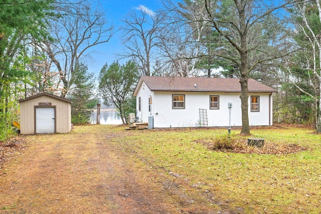 23245 County Rd W, Grantsburg, WI 54840 - view of front facade with a storage unit, an outdoor structure, stucco siding, and roof with shingles