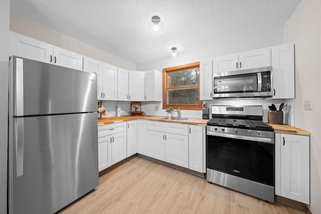 23245 County Rd W, Grantsburg, WI 54840 - kitchen featuring appliances with stainless steel finishes, butcher block countertops, a sink, tasteful backsplash, and light wood-style flooring